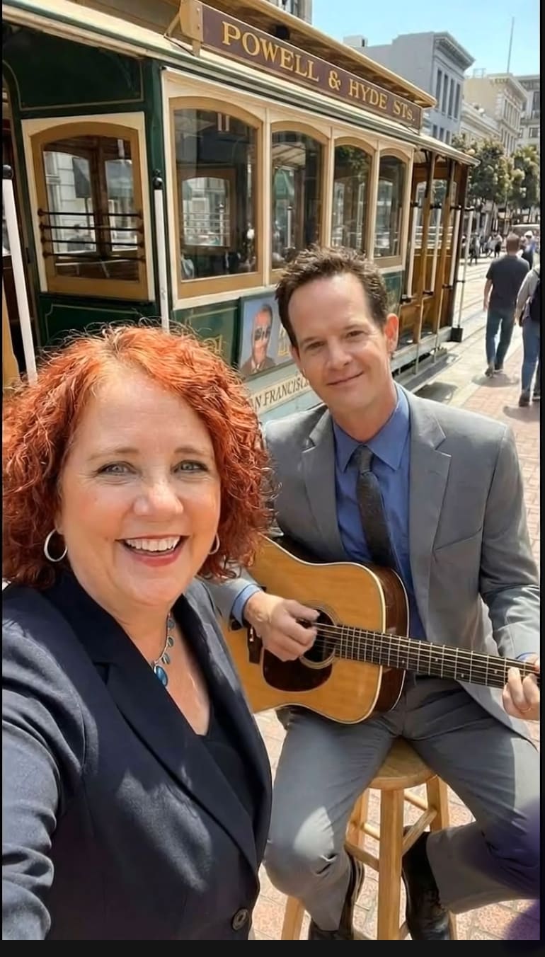 Mariquita with Shawn playing guitar by the San Francisco cable car (AI)